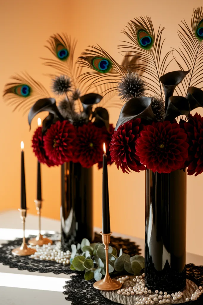 Elegant centerpiece with red flowers, peacock feathers, and black candles on a lace tablecloth.